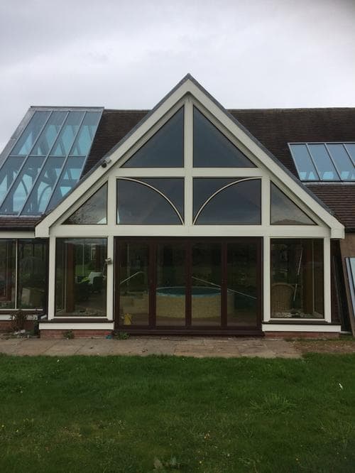 Cream conservatory gable window with dark bi-fold doors