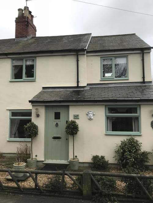 Sage green casement windows on a cream cottage